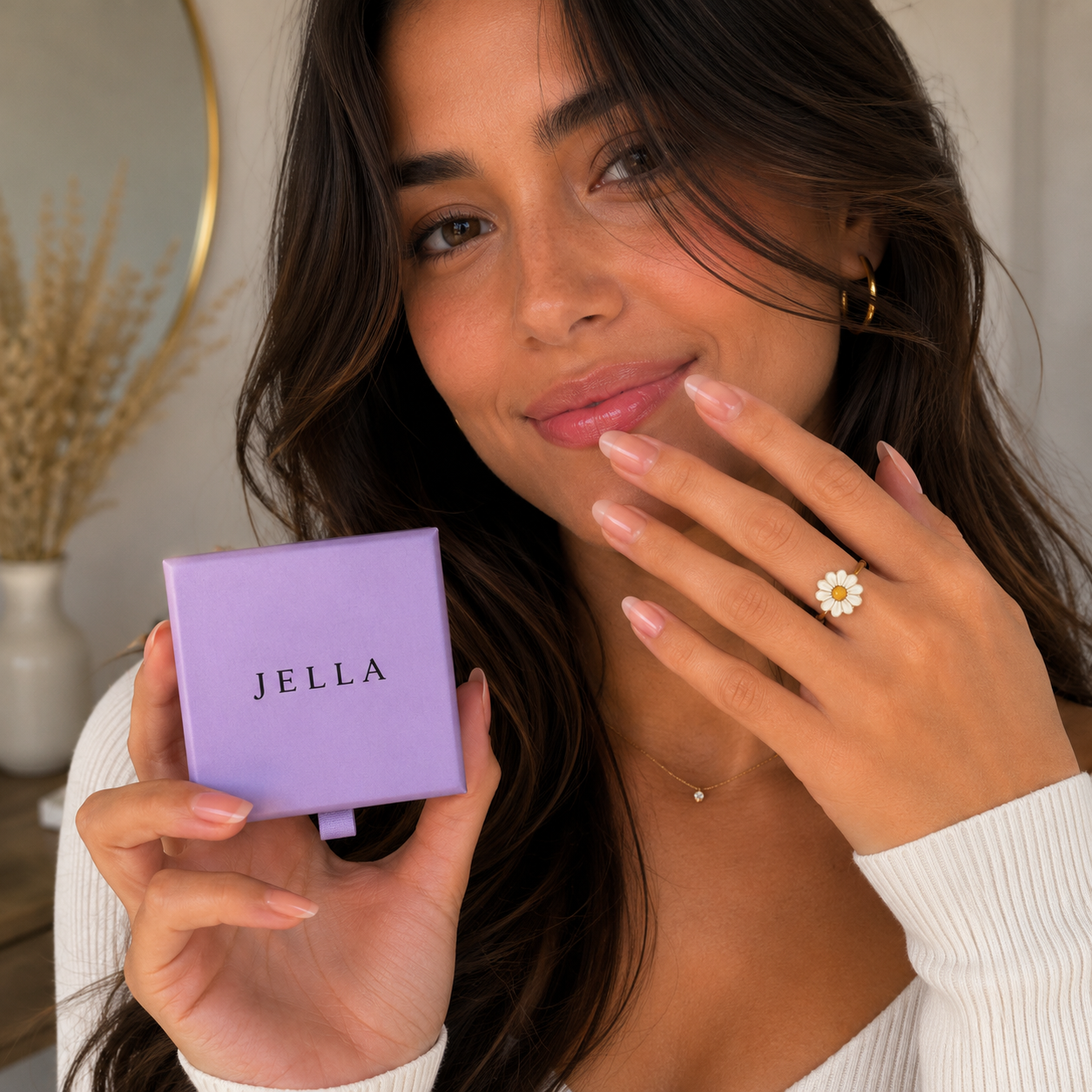 Femme souriante tenant l'écrin violet JELLA avec la bague anti-stress rotative ajustable Léona au doigt